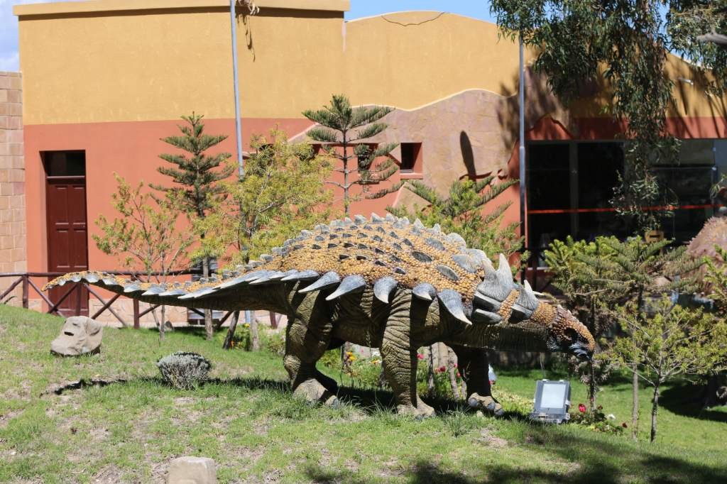 A escasos 300 metros del farallón de huellas de dinosaurio de Cal Orcko, se alza el sorprendente el Parque Cretácico, un complejo turístico único que brinda la posibilidad de conocer a los protagonistas de este legado paleontológico, en uno de los más auténticos escenarios naturales.